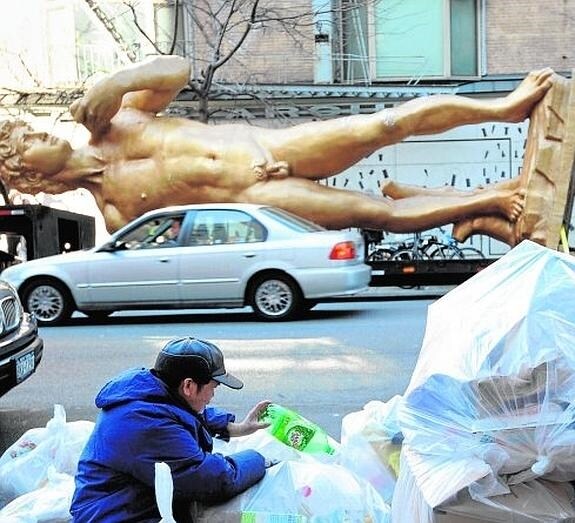 Un hombre rebusca en la basura ante una réplica del David de Miguel Ángel, en Nueva York.