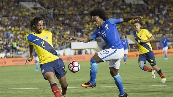 El brasileño Willian disputa el balón con el ecuatoriano Arturo Mina. 