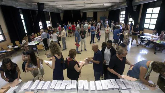 Electores escogiendo su papeleta en un colegio electoral. 