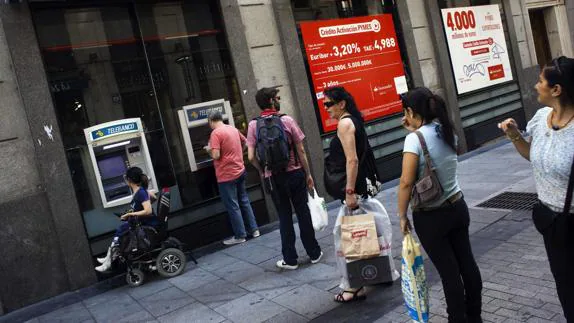 Varias personas hacen cola en un cajero de Madrid.