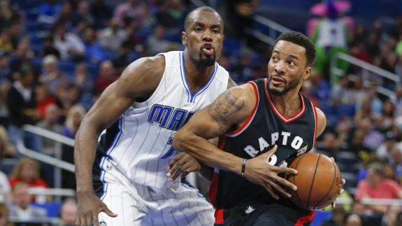 El jugador de los  Raptors Norman Powell trata de zafarse de Serge Ibaka (izq.).