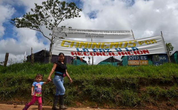 Un rebelde y su hija pasan ante un cartel de reconciliación.