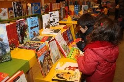 Dos niños observan los libros expuestos en Villa Maravilla, que ayer se inauguró en el Centro Pumarín Gijón-Sur. / JOAQUÍN BILBAO