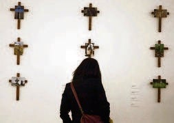 Un joven, con gesto serio, pasa ante una impactante fotografía en blanco y negro de un cuervo posado sobre una lápida. ::                             SERGIO LÓPEZ