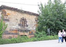 Dos vecinas pasan frente a la capilla de La Ponte, rodeada de maleza. ::                             PABLO NOSTI