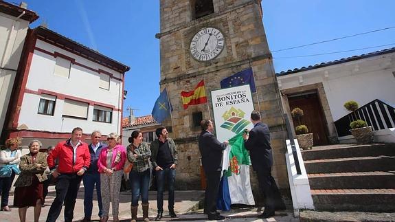 Vecinos de Lastres junto a la placa situada en la Plaza del Reloj y que acredita a la localidad como miembro de 'Los Pueblos Más Bonitos de España'.