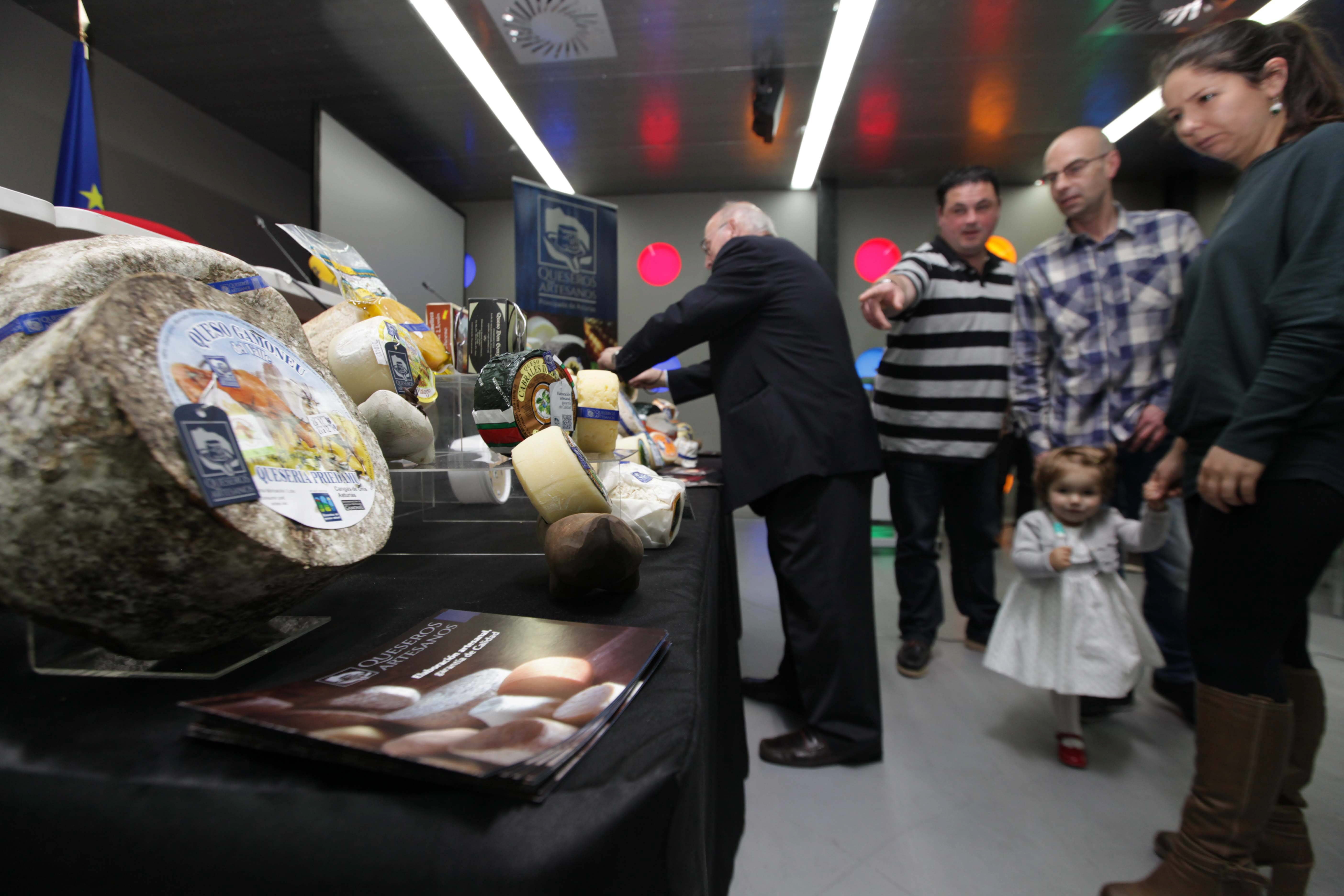 Algunas personas que asistieron a la presentación observan algunos de los quesos dotados de la nueva marca Queseros Artesanos.