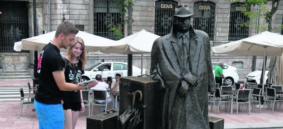 Dos jóvenes recogen uno de los ejemplares en la plaza de Porlier ante 'El viajero' de Úrculo.