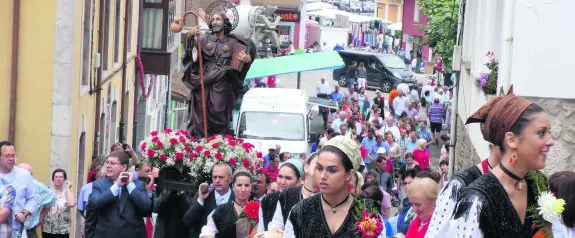 Las andas con la imagen de Santiago por las calles de Posada, camino a la iglesia parroquial y por detrás de las mozas de llanisca. 
