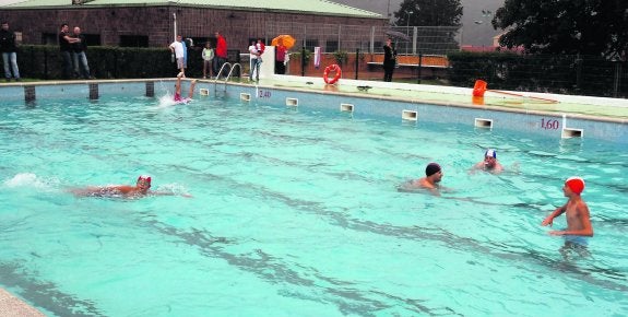 Los primeros bañistas de las piscinas de Riaño, que no se echaron atrás pese al persistente orbayu de ayer. 