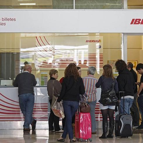 Varios pasajeros esperan en el mostrador de una compañía aérea en el aeropuerto de Asturias