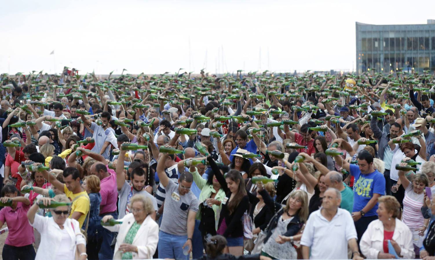 El momento del escanciado simultáneo en la playa de Poniente en Gijón