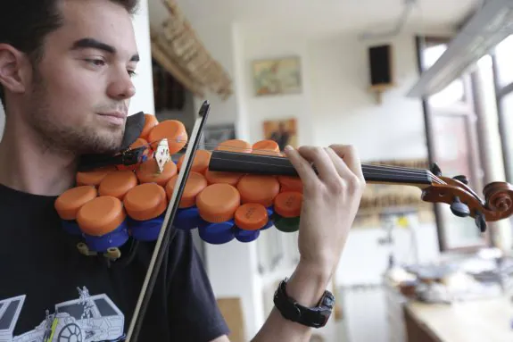 El músico Iyán Méndez toca el violín fabricado con tapones de plástico. 