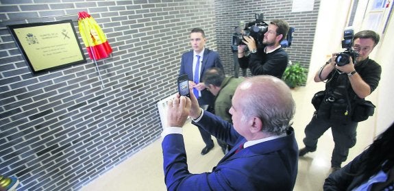 El ministro hace una fotografía con su móvil a la placa de inauguración del nuevo cuartel de Langreo. 