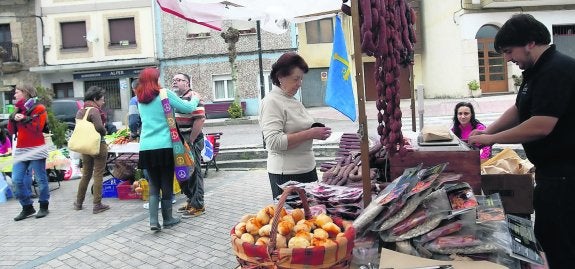 José María Montes, ayer, atiendendo a una clienta en su puesto de embutidos en el Mercáu Yerbatu de San Julián. 