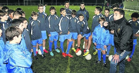 Los jóvenes jugadores siguen las instrucciones de un técnico, con Cervero y Linares al fondo. 