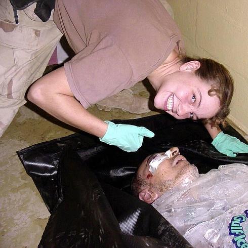 La policía militar estadounidense Sabrina Harman señala sonriente al detenido iraquí Manadel al-Jamadi, envuelto en hielo, en la cárcel de Abu Ghraib.