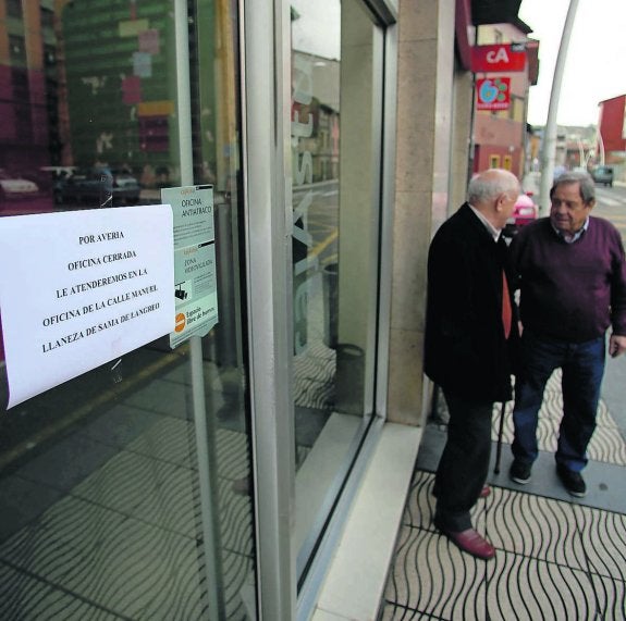 Dos hombres charlan ante la oficina, ya cerrada. 
