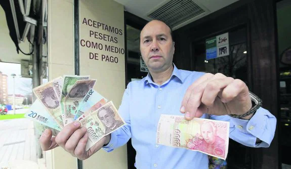 José Manuel Álvarez, con varios billetes de pesetas y euros, a las puertas de la cafetería Samara. 