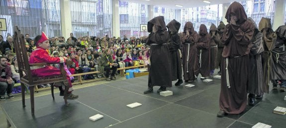  'La línea del tiempo'. Alumnos del colegio Jovellanos representan una escena de la obra vestidos de monjes medievales. Al fondo, los padres y el resto de los estudiantes observan atentamente. 