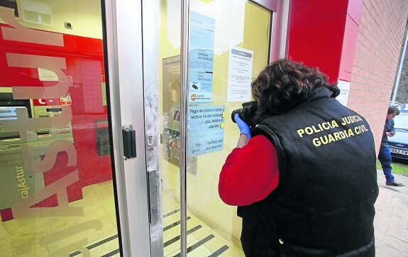 Un guardia realiza varias fotografías en busca del pruebas en la entrada de la agencia. :: j. c. román