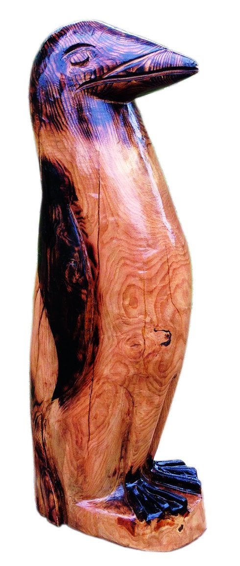 A la izquierda, Radek Golebiewski posa, junto a su compañero Sergio de la Mota, con la mesa y las sillas que esculpió como regalo al bar Espicha Park. A la derecha, podando unas ramas con la rosaleda y el mar de fondo. Junto a estas líneas, una de sus esculturas. 