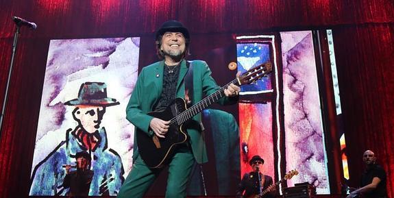 Joaquín Sabina, con su sempiterno bombín, sobre el colorido escenario del Palacio de los Deportes.