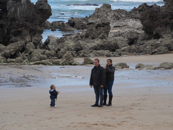 Una familia en la mañana de ayer en la llanisca playa de Toró, una de las que recibirán aportes de arena. 