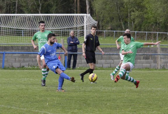 Un jugador del Llanes trata de interceptar un pase de un futbolista del San Jorge. 