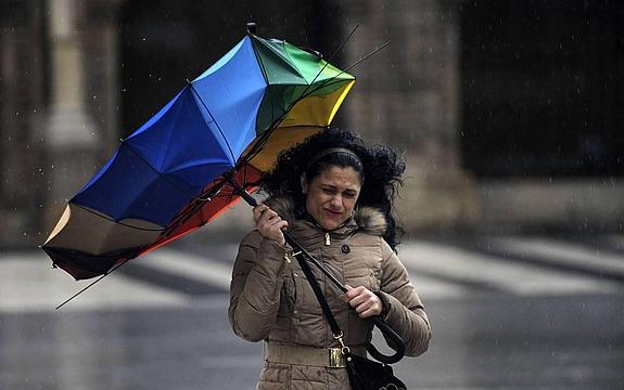 Una mujer intenta sujetar su paraguas, roto por el viento, en Gijón, el pasado mes de enero.