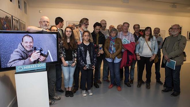 Las hijas de Joaquín Bilbao, María Jesús y Sara -en primer término junto a la pantalla con la imagen de su padre-, acompañadas por compañeros del fotógrafo y autoridades durante la inauguración de la exposición Miraes 2015 en el Museo Barjola de Gijón. 