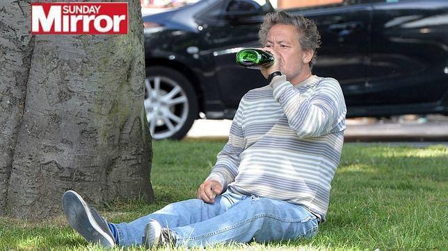 Kenny Sansom bebe una botella de vino en un parque londinense
