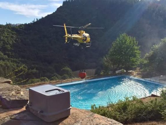Un helicóptero de Bomberos de Asturias carga agua en la piscina municipal de Santa Eulalia. 