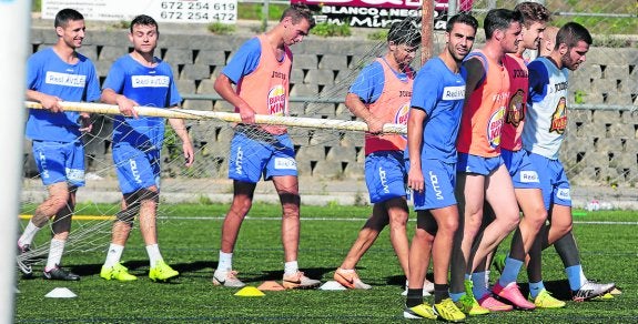 Los jugadores trasladan una portería, con Marcos Torres, de blanco, al frente. 