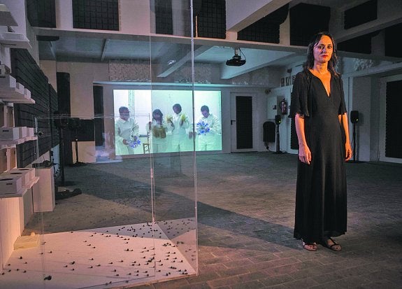 Angélica Liddell, en actitud teatral posa al lado de la urna-ataúd de las abejas. A su espalda, una de las pantallas. La que recrea la coreografía de los apicultores que acaban enterrando a la poeta.