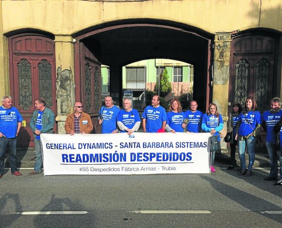 Los despedidos con la pancarta para reclamar su readmisión en la fábrica de armas de Trubia. 