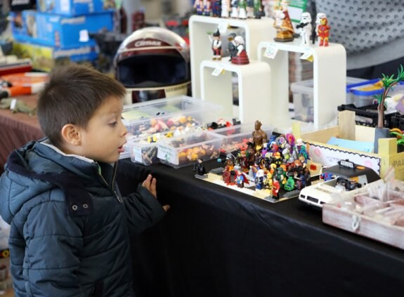 Un niño se fija en una colección de muñecos antiguos. 