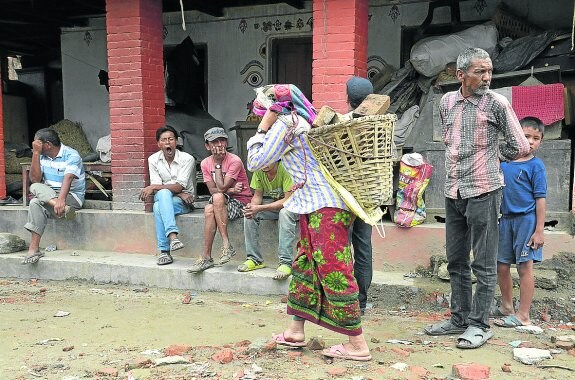 Cada uno de los ladrillos que esta mujer nepalí carga en su cesta pesa casi tres kilos. Mientras, los hombres descansan y uno de ellos bosteza con total tranquilidad. 