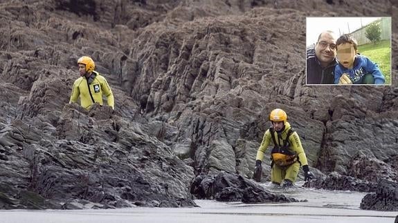 Dos efectivos de Bomberos de Asturias rastrean las rocas de la playa de Frejulfe, aprovechando la bajamar, en busca del pequeño de 20 meses. 