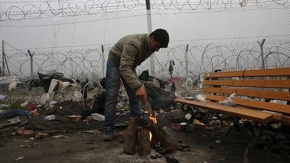 Un refugiado trata de calentarse junto a una hoguera en el campamento provisional de Idomeni, en la frontera entre Grecia y Macedonia.