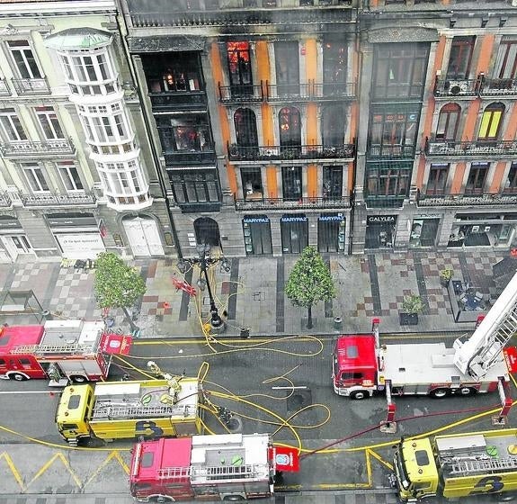 Cubas y camiones de Bomberos de Oviedo y Asturias, situados frente a la fachada del 58 de Uría en pleno incendio.