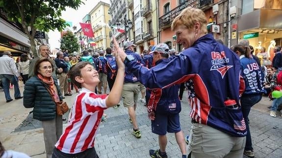 Una de las participantes de EEUU chola su mano con la de un niño con la camiseta del Sporting en la calle de La Cámara.