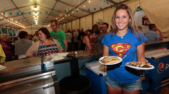 Salida de las primeras raciones de sardinas en la carpa de la fiesta.