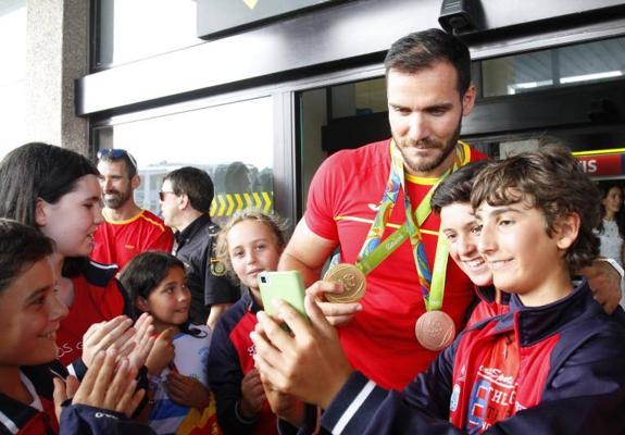 Saúl Craviotto posa, con sus medallas, con unos niños que le recibieron en el aeropuerto.