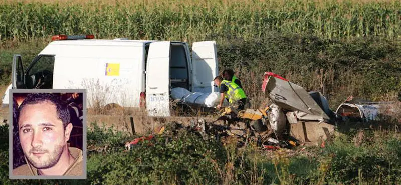 Operarios de la funeraria introducen uno de los cadáveres en una furgoneta, ante los restos destrozados de la avioneta.