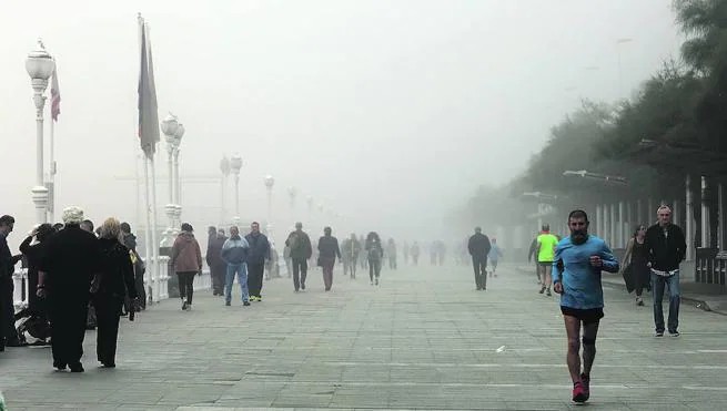 La niebla cubrió la costa gijonesa durante todo el día, pero no impidió que la gente paseara o saliera a hacer deporte por el Muro 