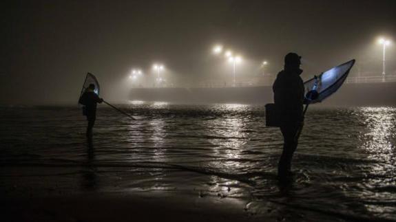 Dos pescadores, a medianoche, en la ría de Ribadesella.