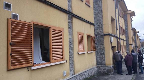 Un grupo de vecinos frente a la vivienda afectada, con las ventanas abiertas.