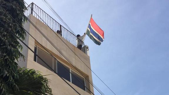 Funcionarios de la Embajada de Gambia levantan una nueva bandera antes de la toma de posesión de Adama Barrow, en Dakar.