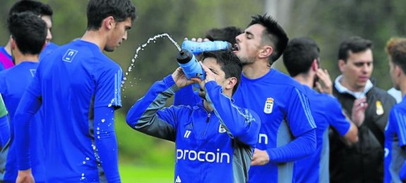 Jonathan Pereira, que regresa a la convocatoria oviedista, bromea con el agua mientras David Costas bebe a su espalda.